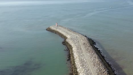 1851-Cabo-de-Santa-Maria-lighthouse-at-the-end-of-a-rocky-spit-in-the-Portuguese-ocean-on-a-Sunny-Day,-Drone-Aerial