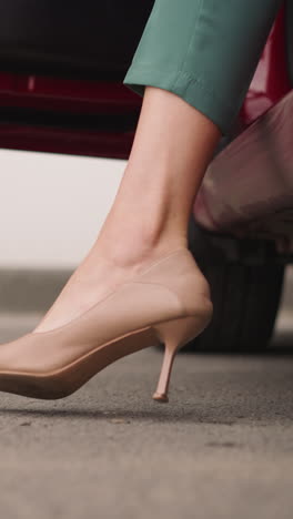 stylish woman in elegant high heel shoes opens door getting out of car. businesswoman arrives at work to modern office building closeup slow motion