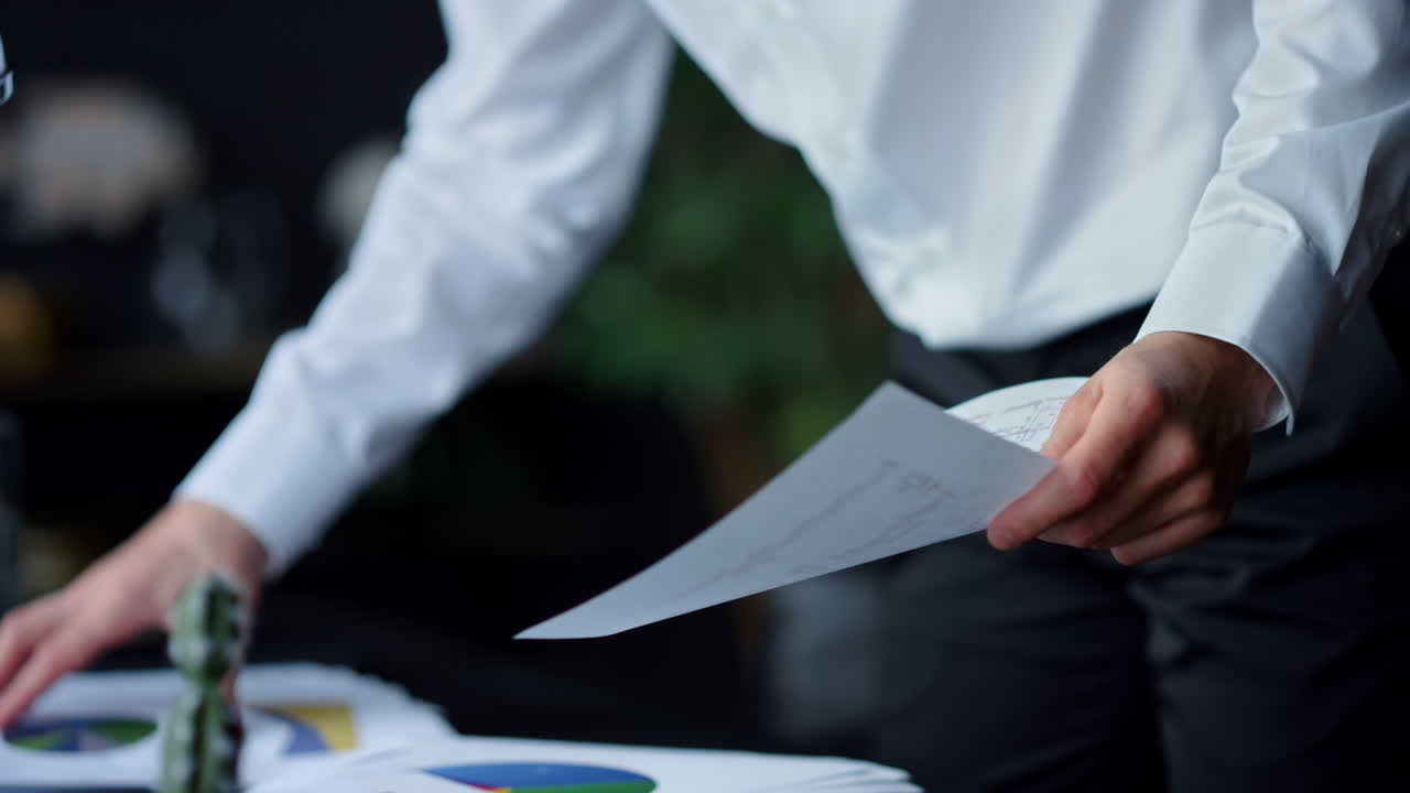 Unrecognizable businessman pointing in document indoors. Man hands holding paper