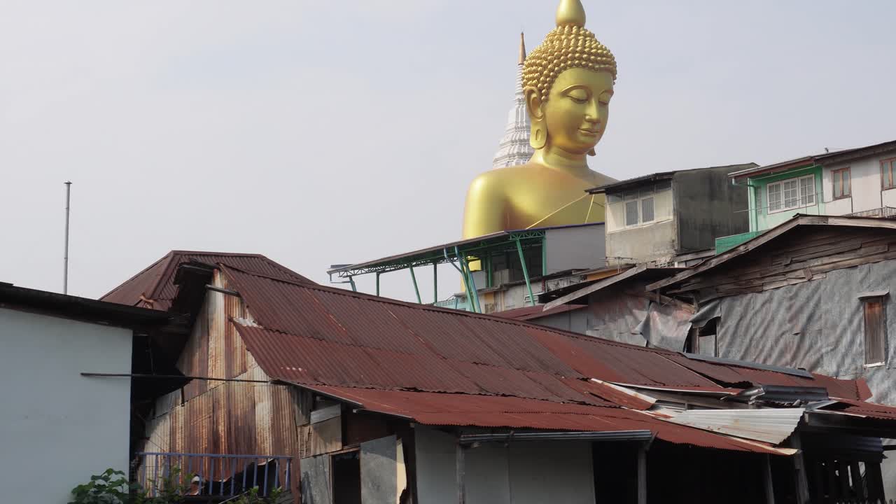 un barrio viejo y gastado en los remansos de bangkok, en la parte pobre de la ciudad en la capital de tailandia en asia, con una enorme estatua de buda en el fondo