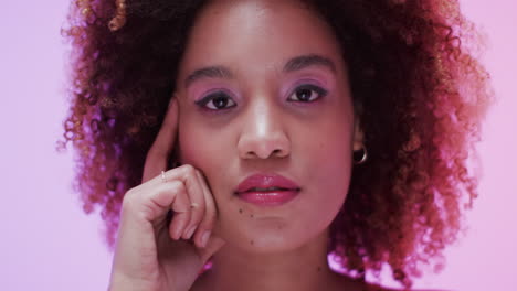 mujer biracial con cabello oscuro y rizado en luz rosa, cámara lenta