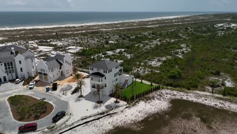 Backward panoramic drone movement from the coastal development extending into sandy coastline near open ocean bay, Panama City Beach, Florida, USA
