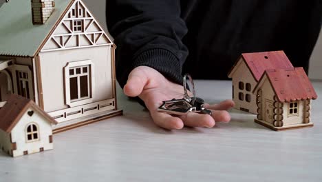 keychain in the form of houses with keys to a new apartment in your hand. purchase of real estate. beautiful keys to the new building