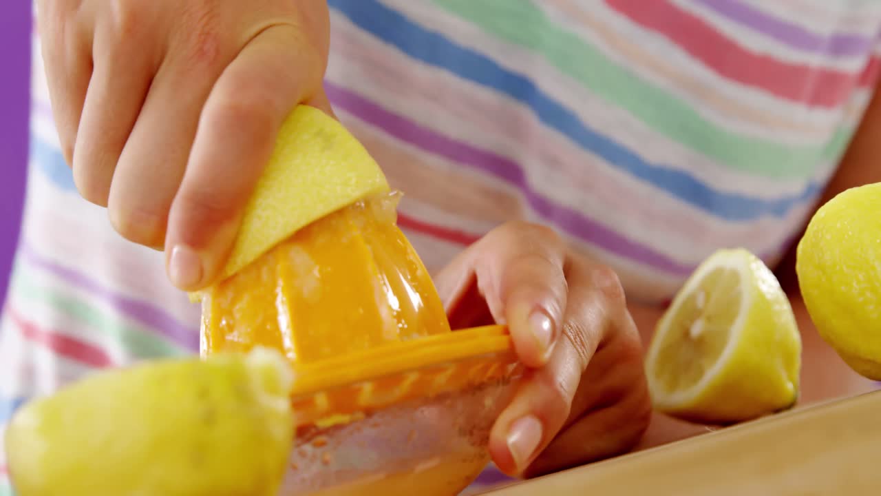 보라색 배경 에 대해 주스기 에서 라임 주스 를 준비 하는 여자