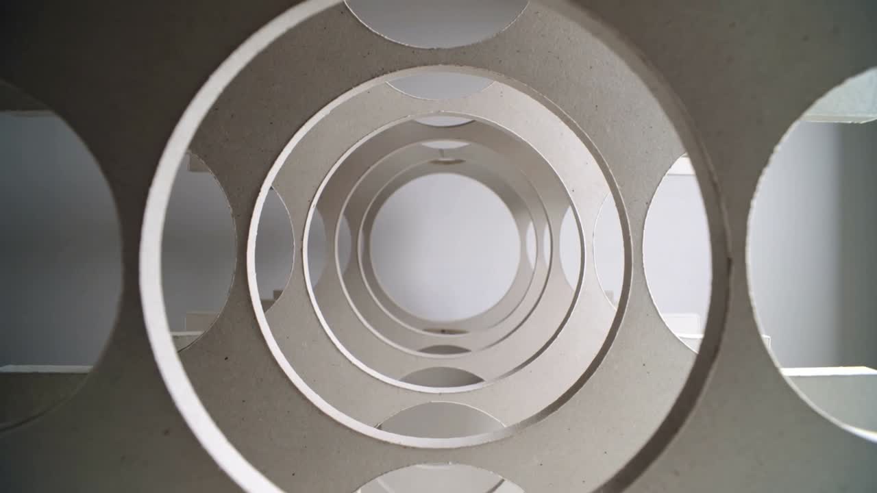 Telecamera in movimento che mostra sagome circolari impilate che scivolano verso l'obiettivo in studio, rivelando la texture.