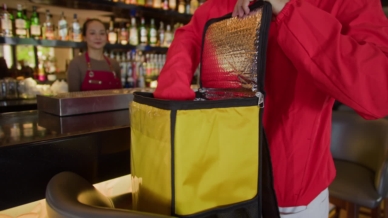 Addetto alle consegne che riceve una borsa con cibo da un dipendente del bar