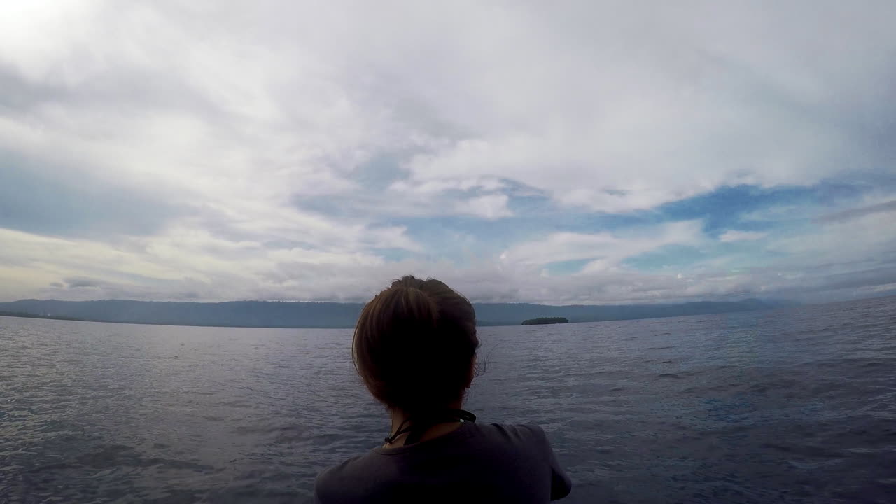 mujer montando en la parte delantera de un barco durante un clima sombrío