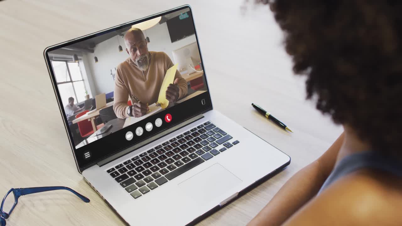 Afroamerikanische Frau benutzt Laptop für Videokonferenz, mit Geschäftskollegen auf dem Bildschirm
