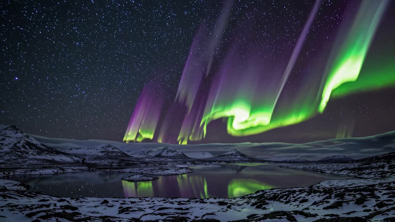 A mesmerizing wide-angle video captures the vibrant green Northern Lights dancing over snow-capped