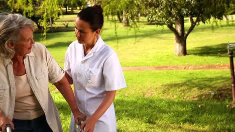 nurse talking to woman using walker outside