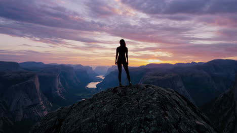 woman on mountain peak at sunset over fjord