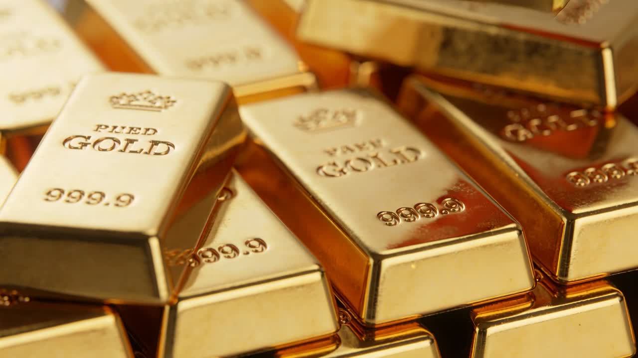 La telecamera si muove e luci calde rivelano lingotti d'oro impilati su uno scaffale espositivo, mostrando il marchio di purezza.