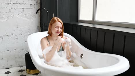 mujer alegre jugando con espuma en la bañera