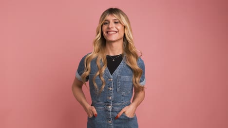 happy transgender woman in denim dress against pink background