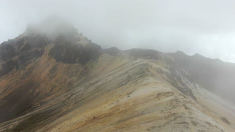 Drone-flying-through-cloud-to-reveal-a-volcanic-rock-mountain-in-the-Andes