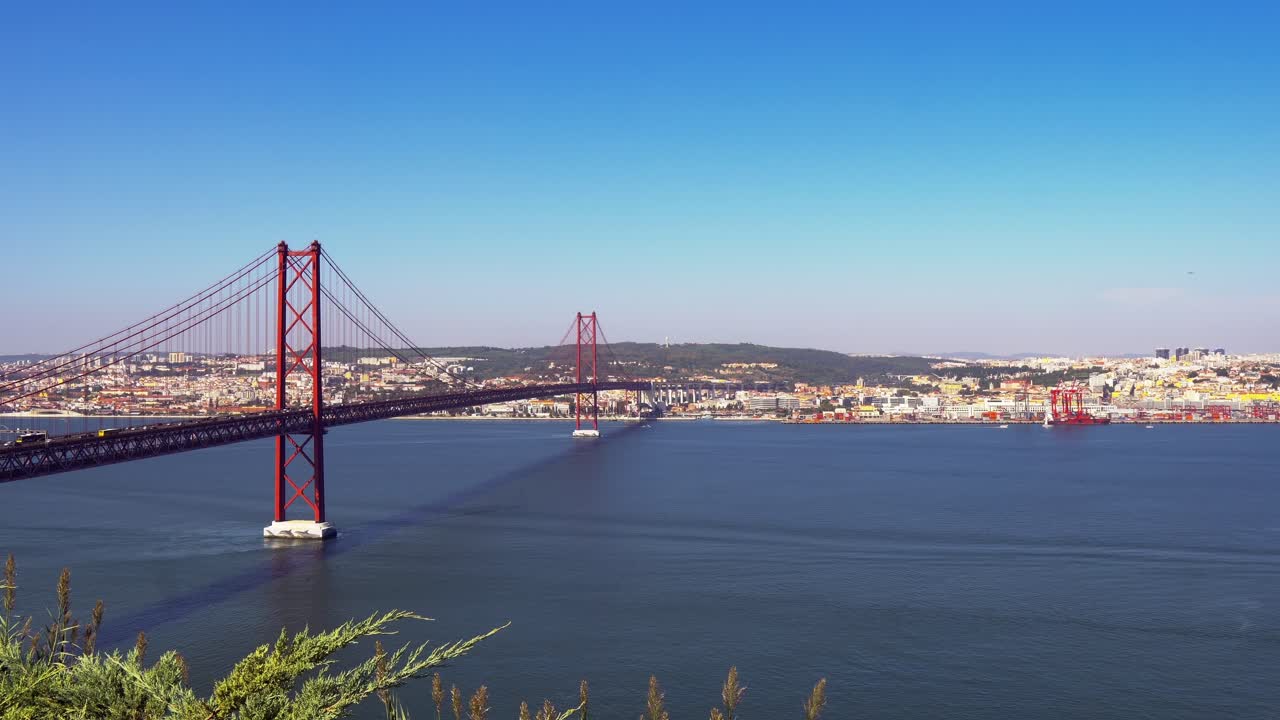 Incredibile architettura del ponte sospeso 25 de Abril e traffico di passaggio di giorno, con vista su Lisbona sullo sfondo, Portogallo