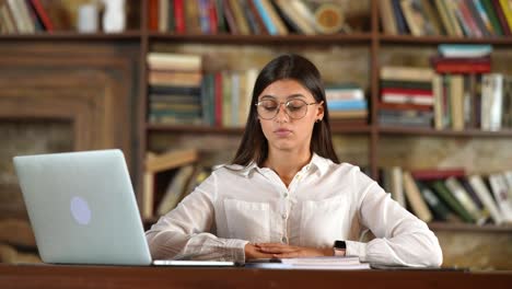 una mujer joven estudiando en una biblioteca.