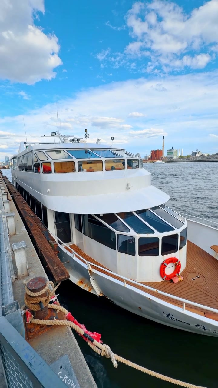 Nova Iorque, EUA, 18 de maio de 2026: Proa de um iate atracado no East River perto da Ponte de Manhattan, Nova Iorque. Convés de teca, boia salva-vidas laranja, cordas e a orla marítima do Brooklyn sob céu nublado.
