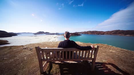 Amplia-Vista-Trasera-Del-Hombre-Sentado-En-Un-Banco-Disfrutando-De-La-Vista,-Erraid-Island,-Escocia