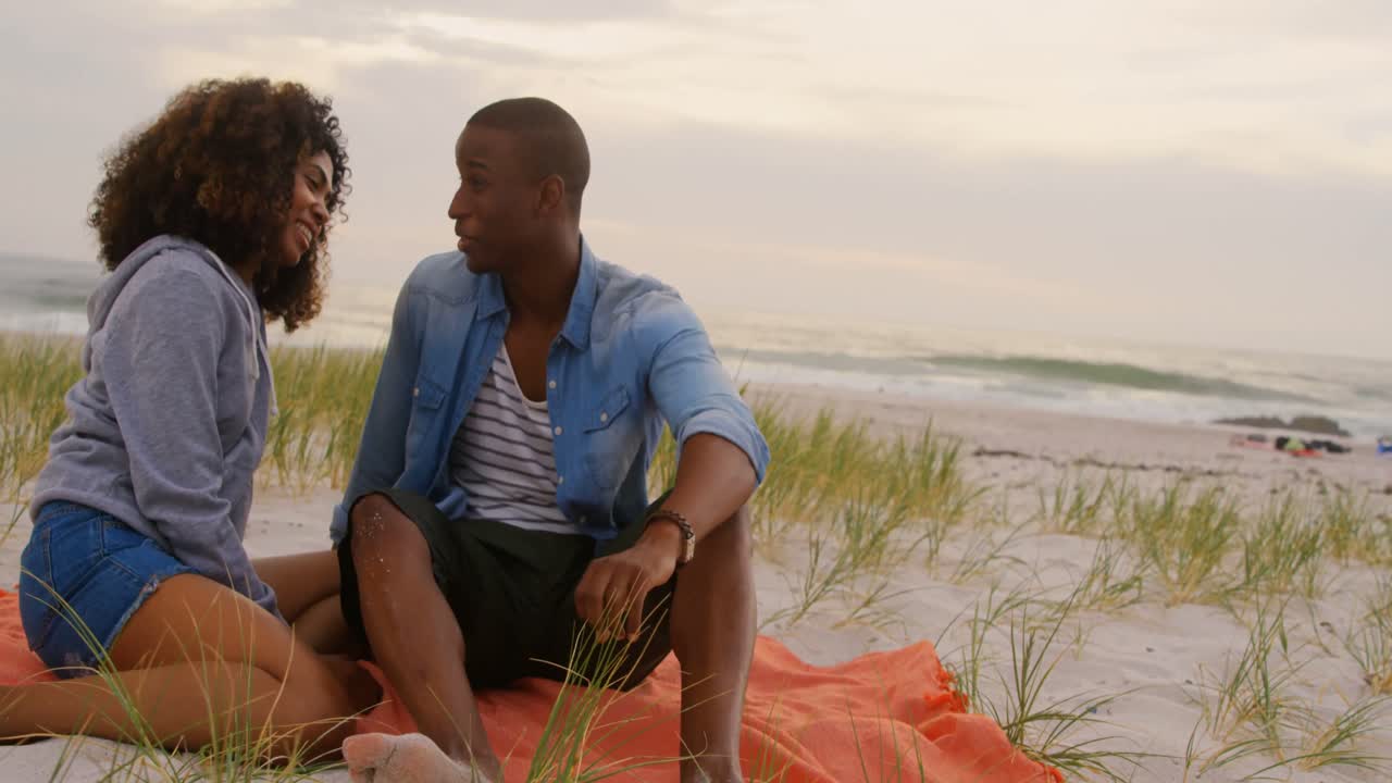 Front view of African american couple interacting each other on the beach 4k