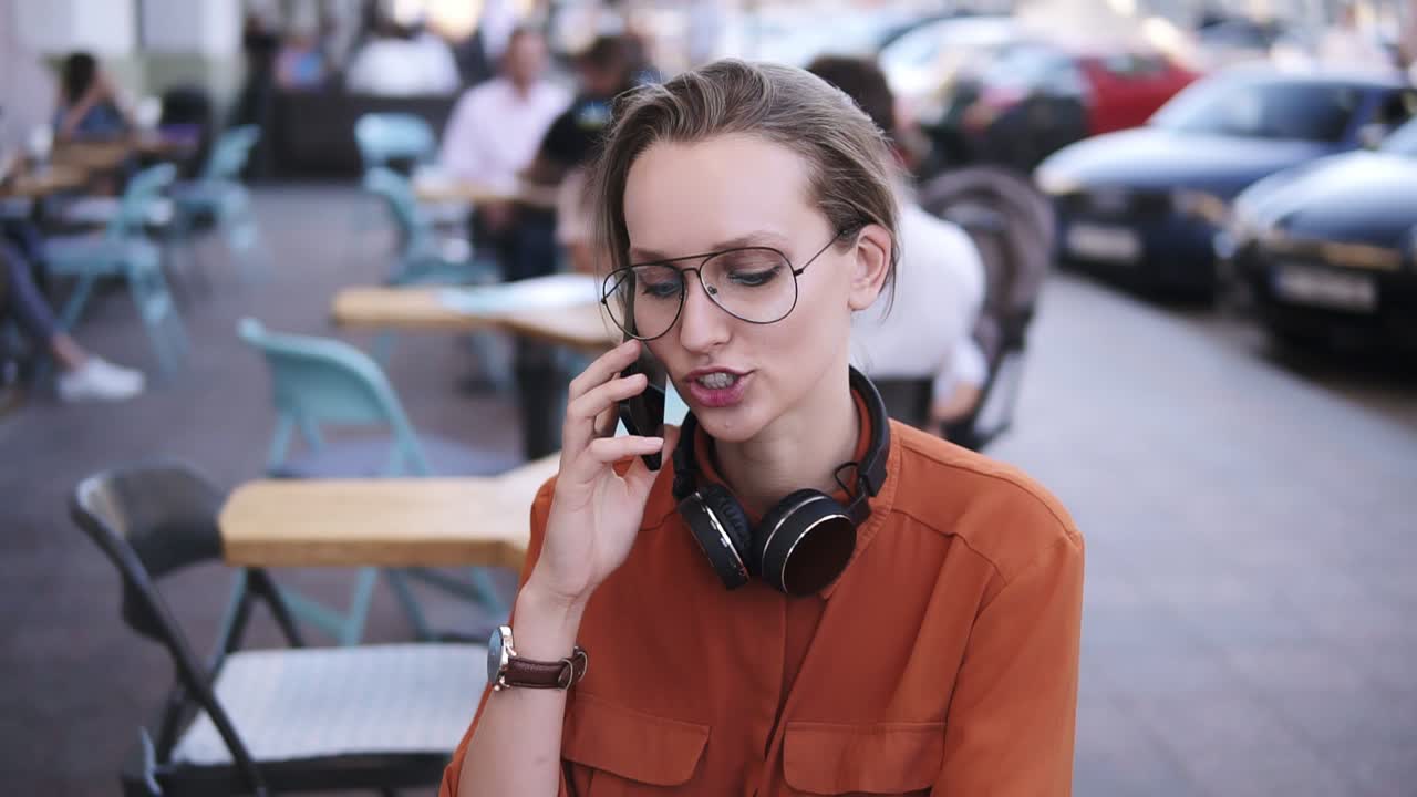 mujer de teléfono inteligente hablando por teléfono mientras estaba sentada en una cafetería. ella está sonriendo. hermosa mujer joven teniendo una conversación casual en