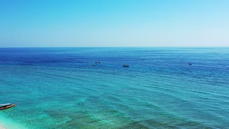 Paisaje-Marino-Tranquilo-Con-Aguas-Claras-Y-Tranquilas-De-La-Laguna-Turquesa-Con-Barcos-Anclados,-Lavando-Una-Tranquila-Playa-De-Arena-Blanca-En-Bali