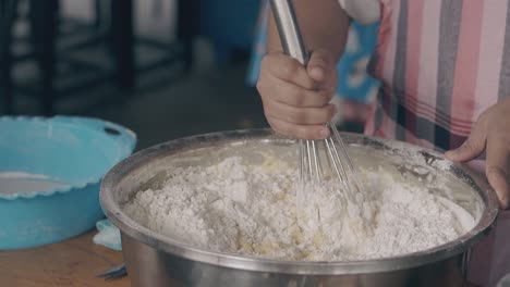 chef mixes ingredients for dough with whisk at table closeup