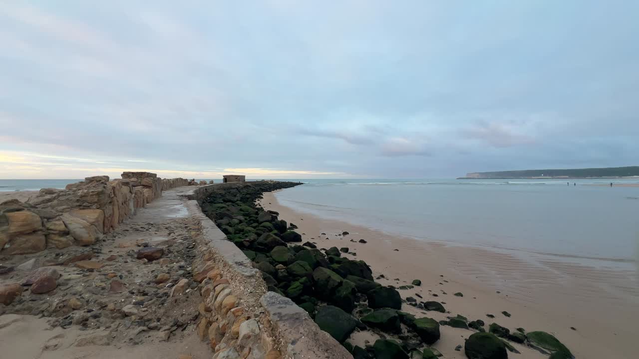 wide view of rocky beach shore with a natural path, gentle sunset atmosphere