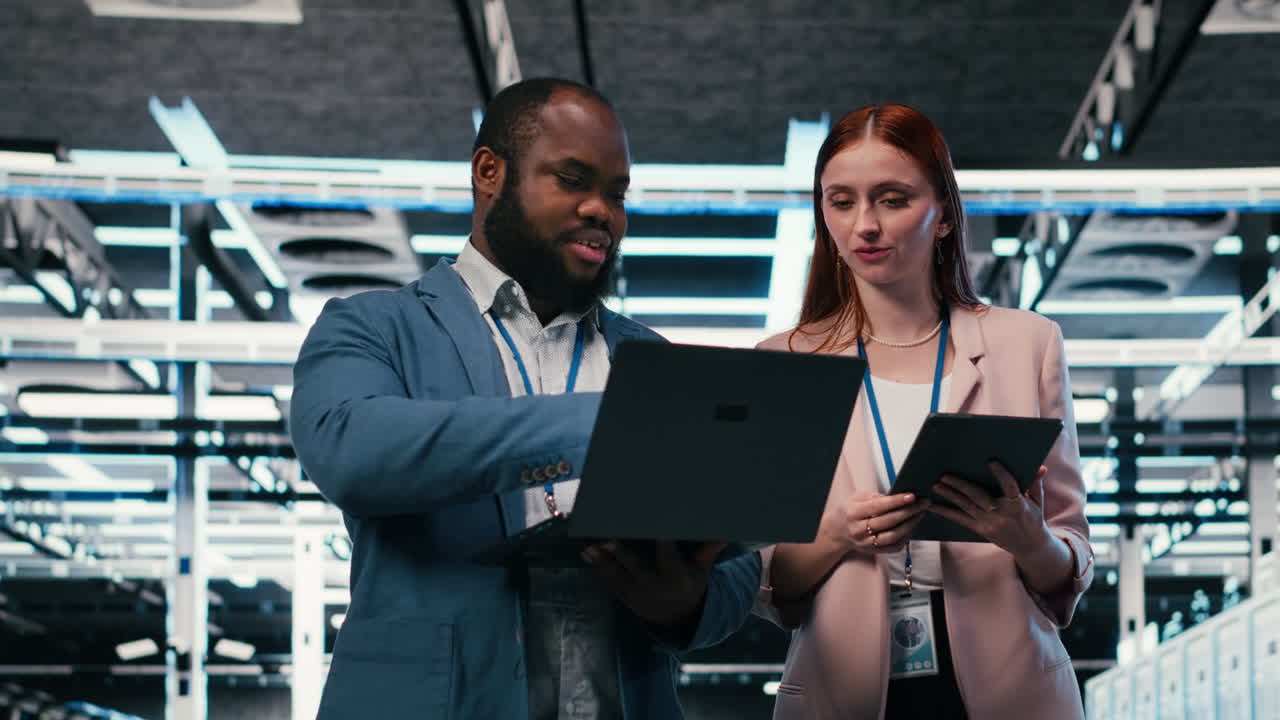 IT-professionelle samarbejder i datacenter med bærbar computer og tablet