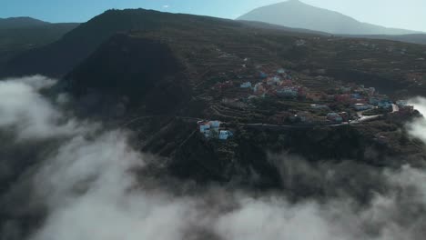 establishing aerial shot of village on cloudy mountain peak, spain