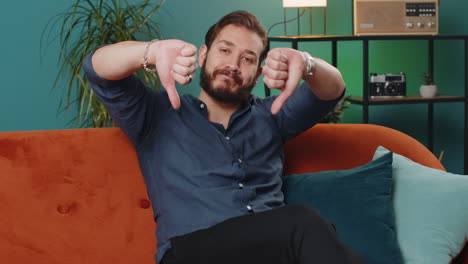 upset lebanese man showing thumbs down dislike bad work disapproval dissatisfied feedback at home