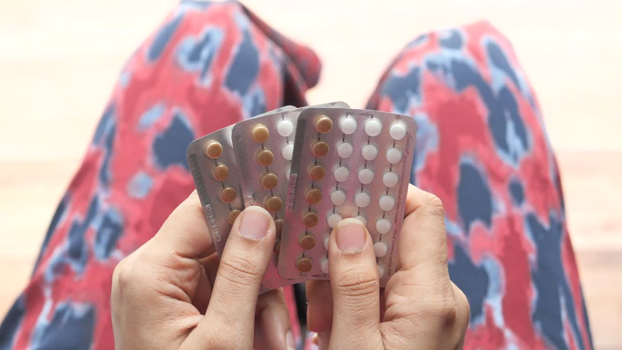 Mulher segurando pílulas anticoncepcionais