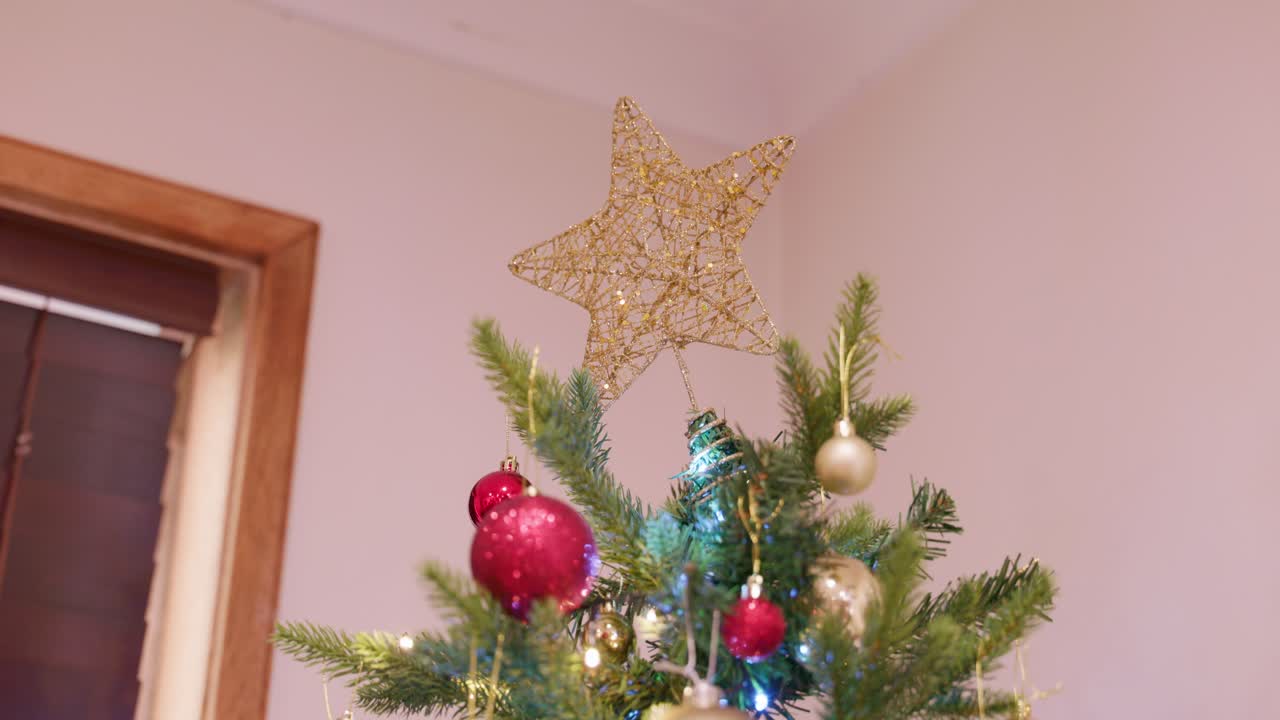 A glowing gold star tops a festive Christmas tree with lights, creating a classic holiday centerpiece.