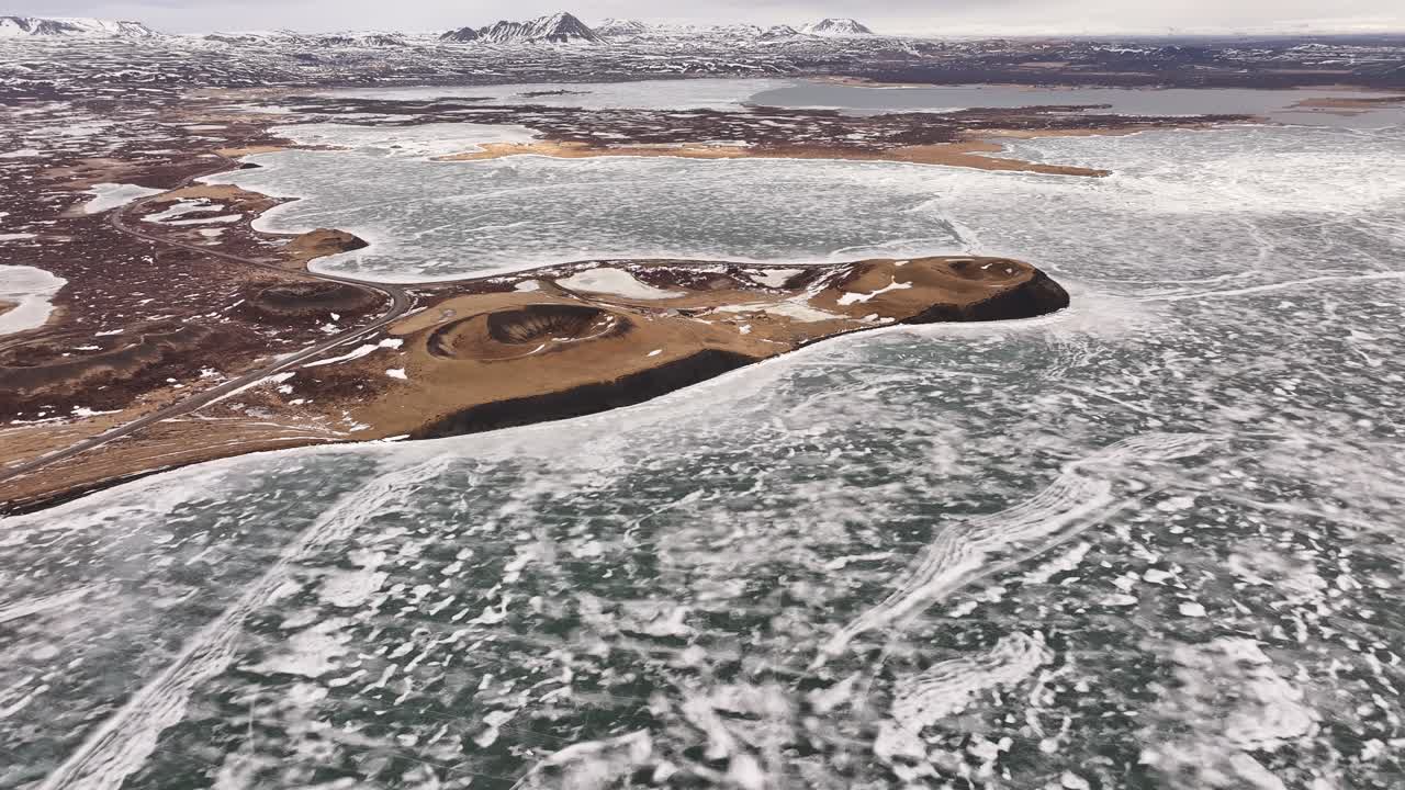 Aerial drone shot of ice-covered terrain and frigid landscape at Skútustaðir on Lake Mývatn in the village of Reykjahlíð, Iceland.