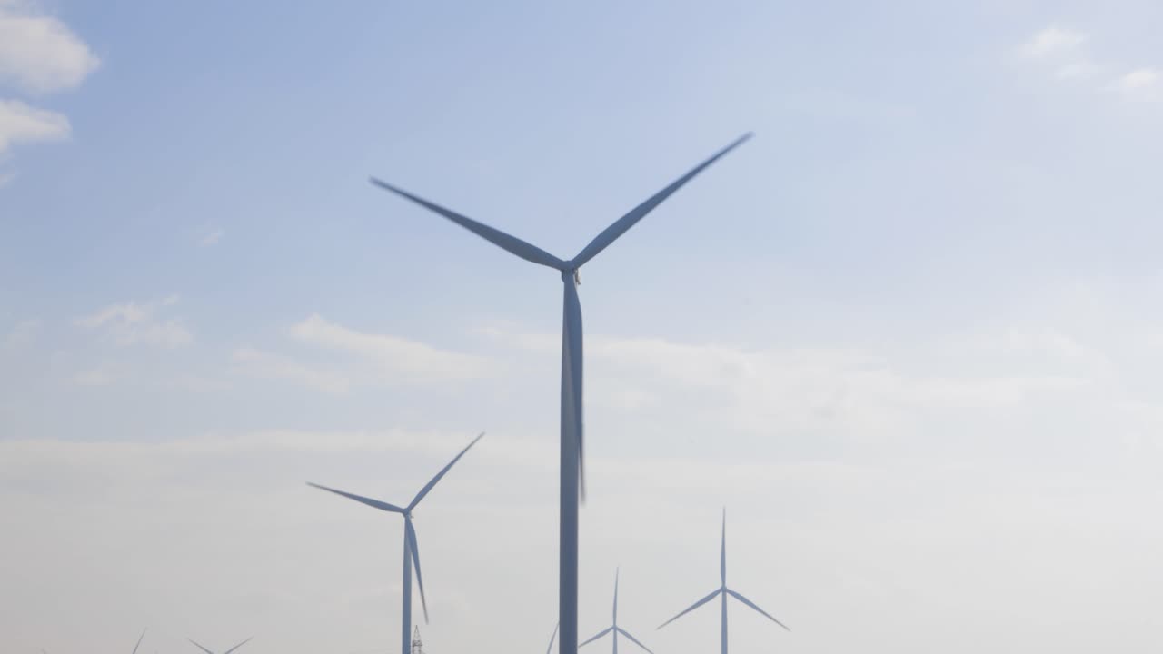 밝은 흐린 하늘을 배경으로 프로펠러가 회전하는 루마니아의 풍력 발전소에서 에너지를 생산하는 풍력 터빈, 중간 샷