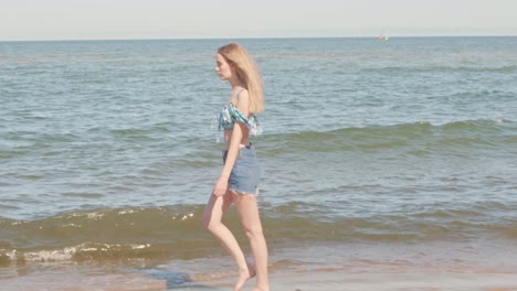 Junge-Blonde-Frau-Zu-Fuß-Am-Strand-An-Der-Küste