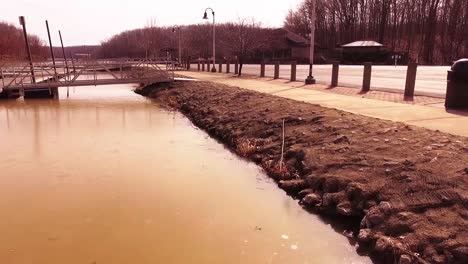 aerial footage rolling along a rocky shore at an icy lake during the winter at a state park