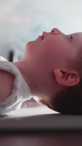 cute little boy takes quick break before lifting heavy barbell. sweet toddler lies on floor against fake mist spreading in gym at bright light slow motion
