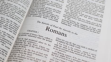 close up shot of bible page turning to the book of romans