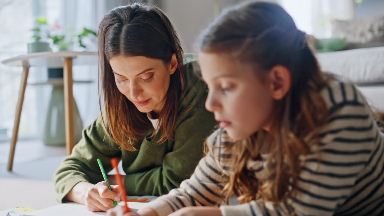 Madre e figlia che disegnano immagini usando le matite, condividendo un hobby insieme in primo piano.