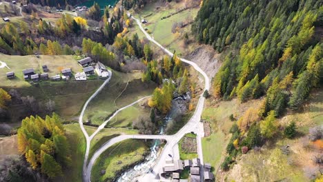 aerial footage above swiss village in autumn : fall with mountains and a river on the background