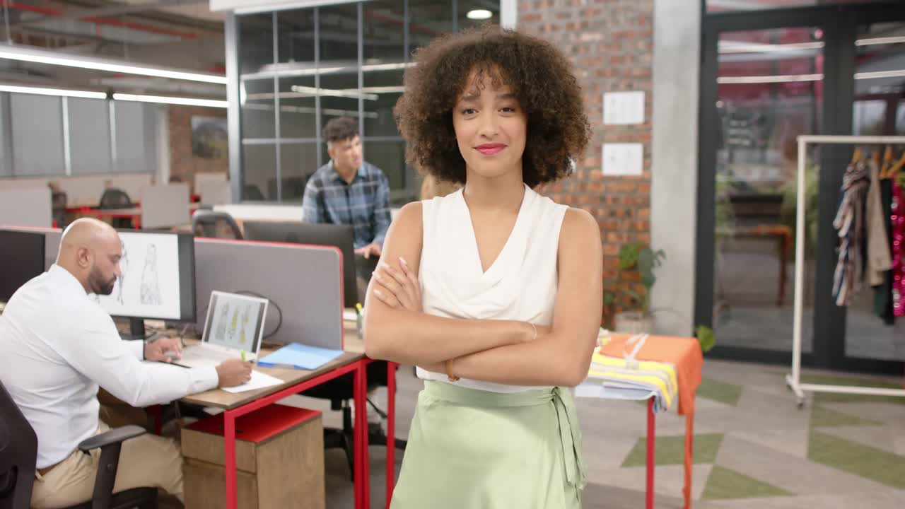 retrato de una feliz diseñadora biracial con diversos colegas en un estudio de moda, en cámara lenta