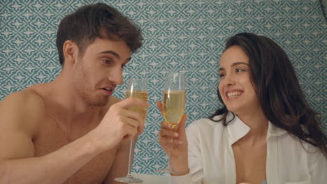 cute couple sipping champagne in bed