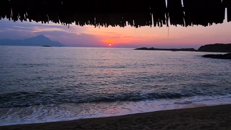 sunrise above sea and waves breaking on sandy beach