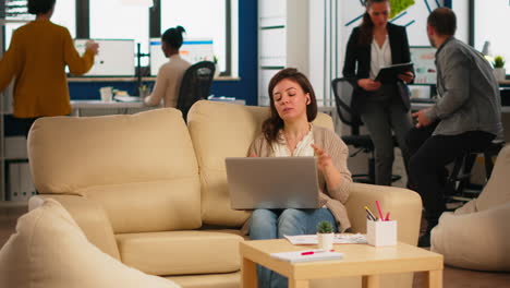 mujer de negocios hablando durante una videoconferencia llamando desde una computadora portátil sentada en el sofá