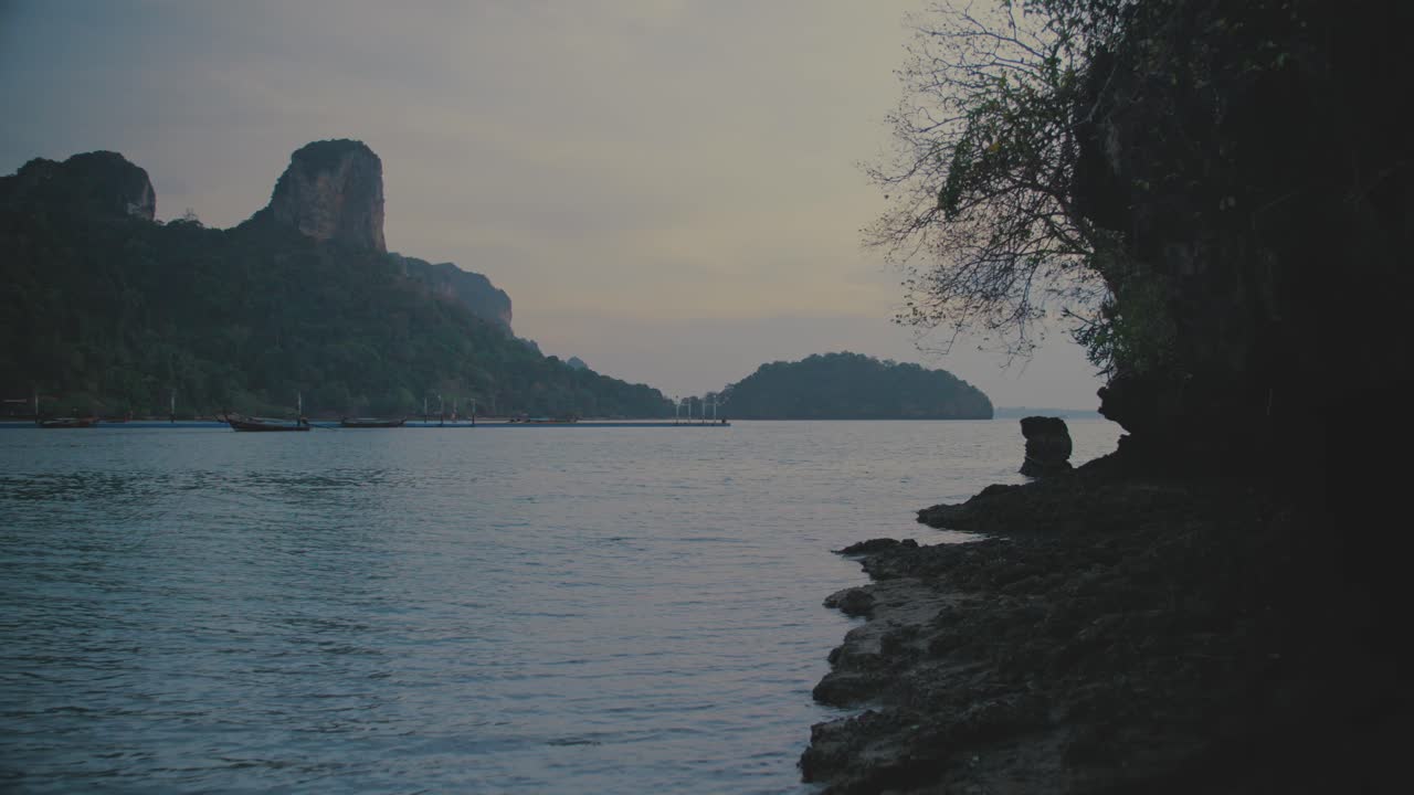 평온한 저녁 해가 지는 동안 바위가 있는 해변 근처에서 산책하는 pov