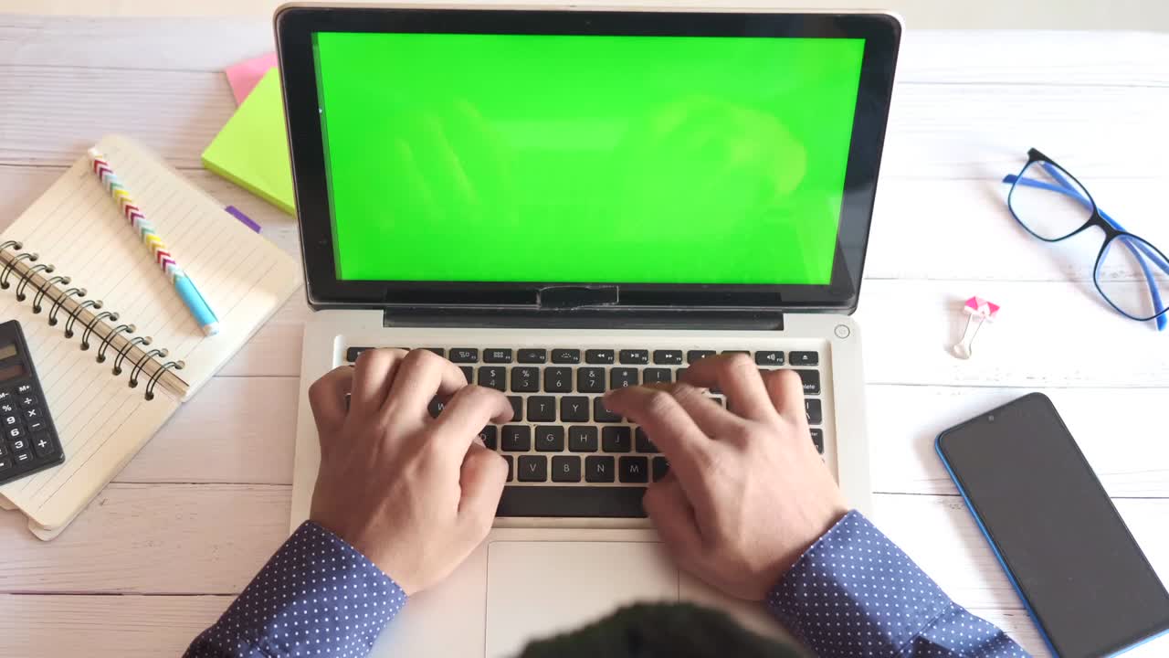 top view of young man using laptop with blank screen on office desk.