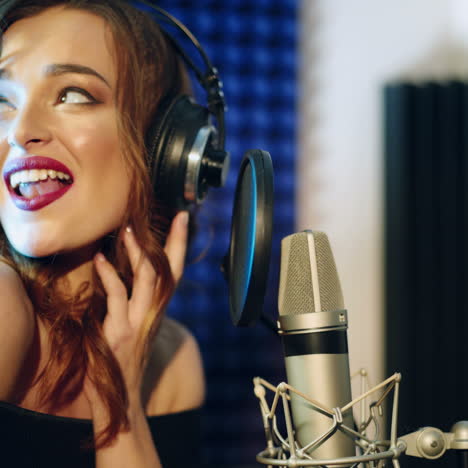 vinnitsa, ukraine - may 2019: young woman recording a song in a professional studio. the girl sings into the microphone.