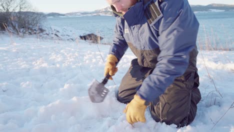 Mann-In-Handschuhen-Schneidet-Mit-Schaufel-Zweige-In-Den-Boden,-Bevor-Er-Das-Zelt-Auflegt