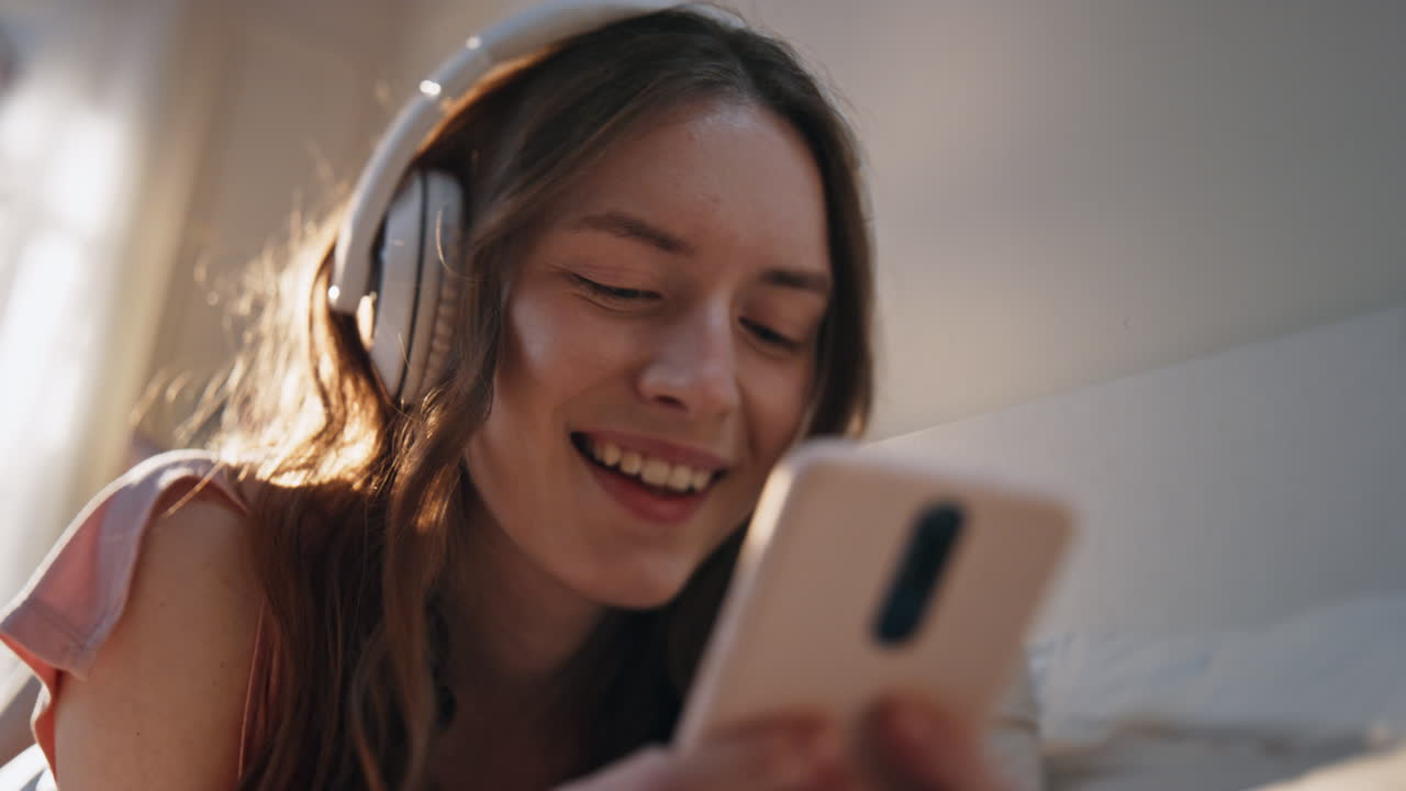 chica despreocupada escuchando auriculares música de primer plano. mujer sonriente navegando por móvil